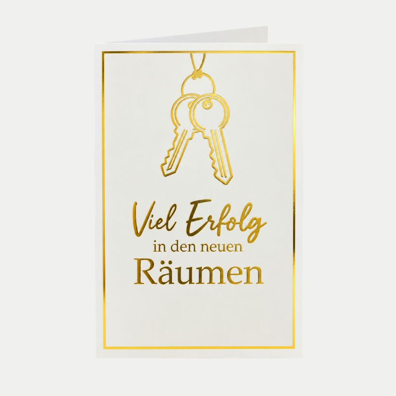 Glückwunschkarte für neue Geschäftsräume mit goldenem Schlüsselmotiv, stehend auf einem modernen Schreibtisch